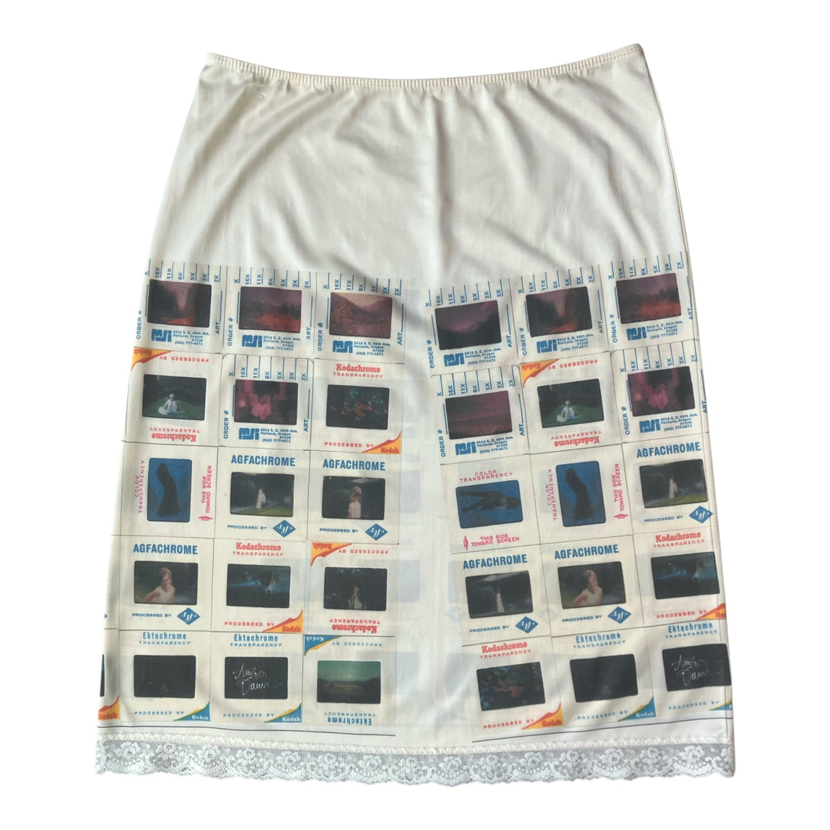 An off-white or cream-colored skirt featuring a printed collage of vintage film stills and posters with the word 'kodachrome' repeated, finished with a lace hem.