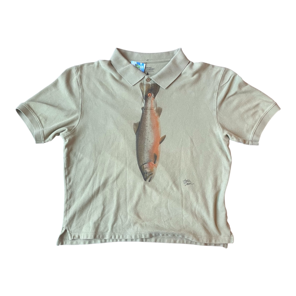 A short-sleeve polo shirt in a light beige green or sand color, featuring a large graphic print of a fish on the front. The shirt is laid flat against a solid white background.