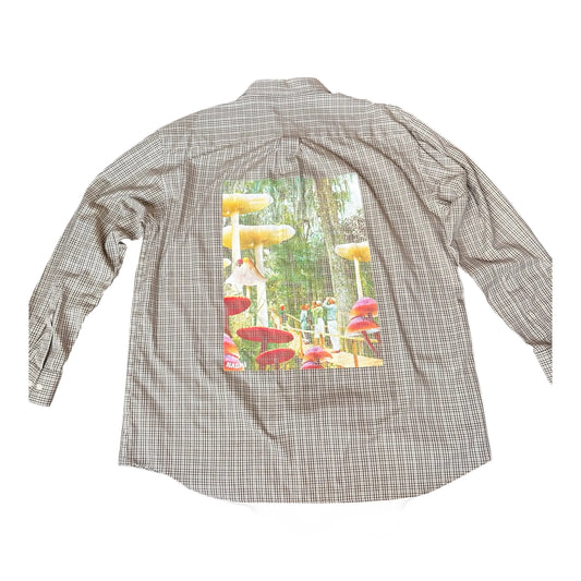 A long-sleeve plaid button-up shirt shown from the back, featuring a large rectangular graphic print of a whimsical mushroom forest on the back panel.