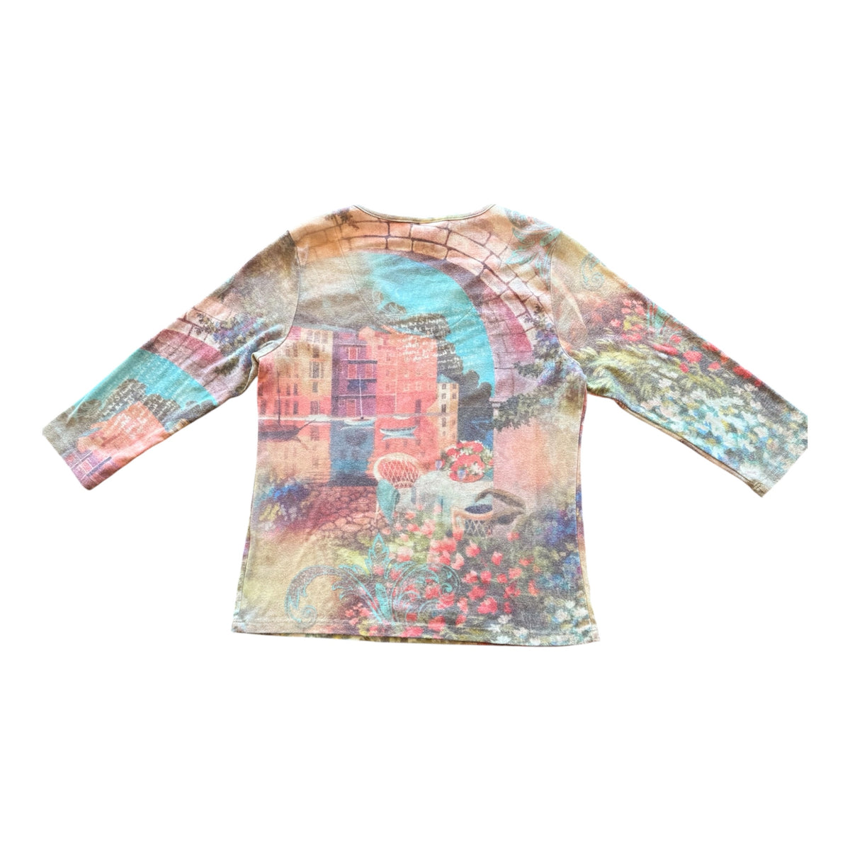 A long-sleeve crewneck shirt featuring a vibrant, multicolored artistic print of a European street scene with buildings, flowers, and a bicycle, displayed flat against a white background.