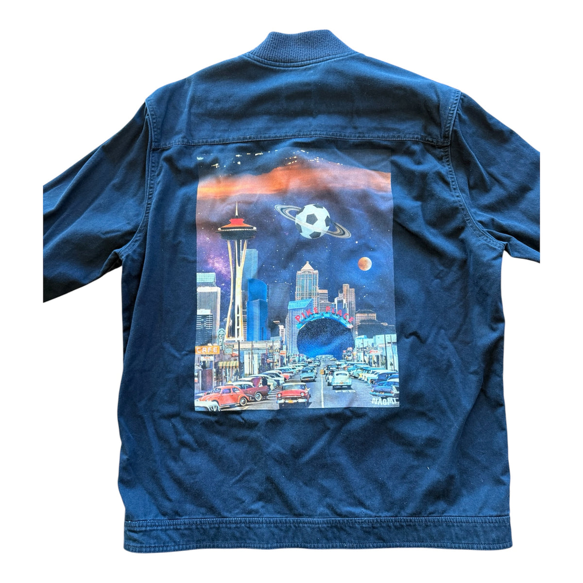 A blue jacket shown from the back, featuring a large, colorful graphic print of a sci-fi Seattle cityscape with the Space Needle, a ringed planet, and a space tunnel.