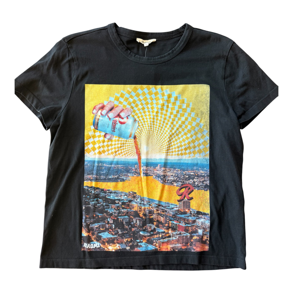 A black short-sleeve graphic t-shirt featuring a retro-style print of a hand pouring Rainier Beer from a can onto a cityscape, with a yellow and white checkerboard sunburst pattern above.