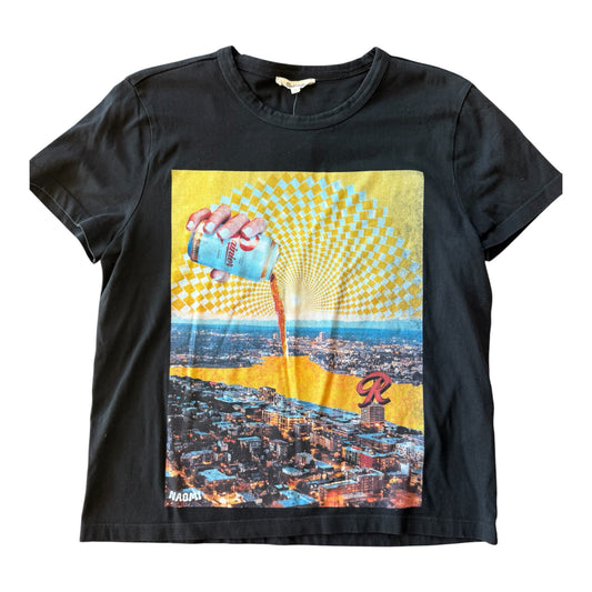 A black short-sleeve graphic t-shirt featuring a retro-style print of a hand pouring Rainier Beer from a can onto a cityscape, with a yellow and white checkerboard sunburst pattern above.