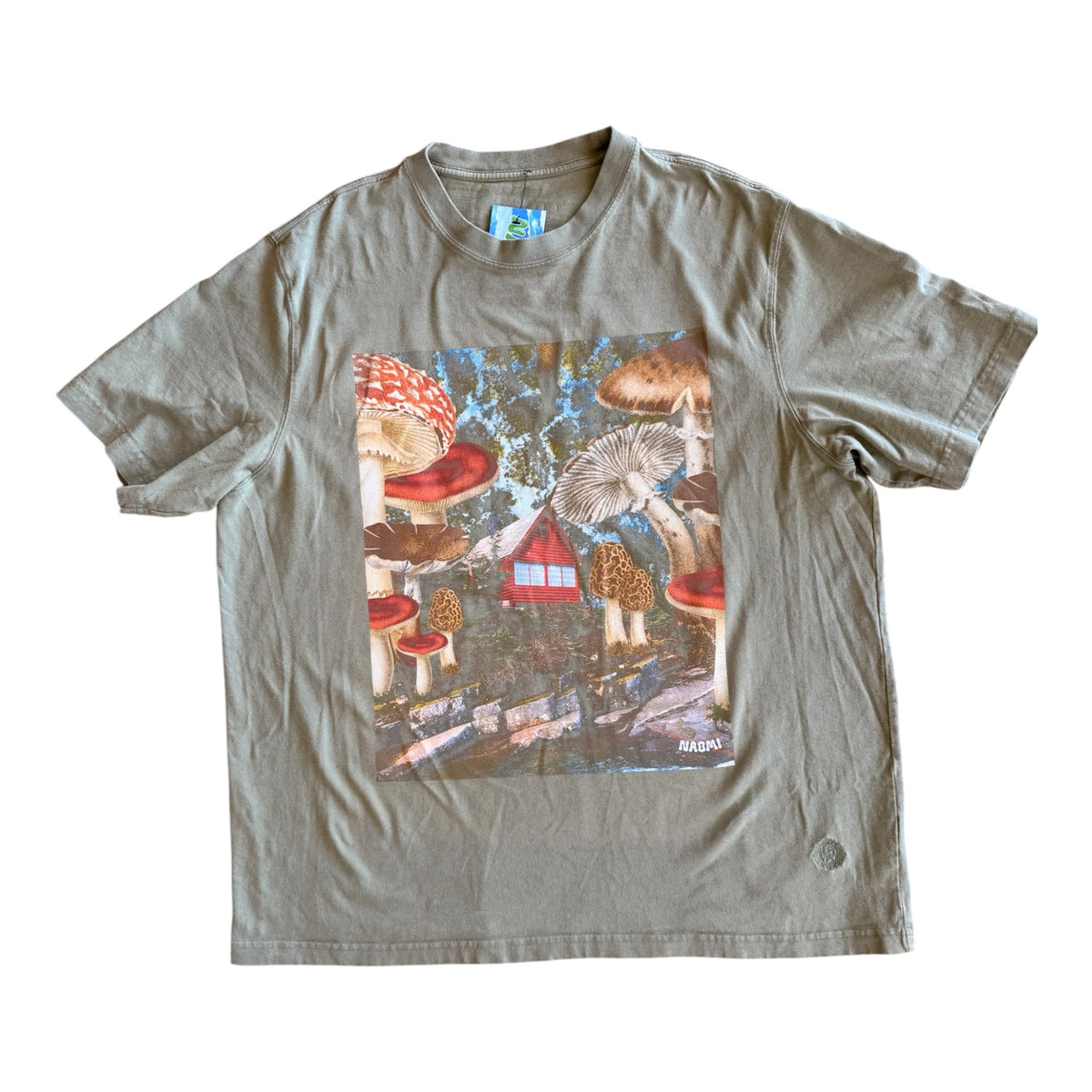 A vintage olive green short-sleeve t-shirt with a large square graphic print on the front depicting colorful mushrooms, a small red house, and a blue sky.