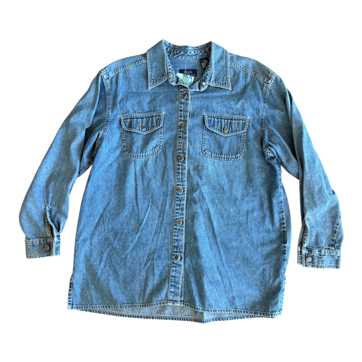 A light blue denim long-sleeve button-up shirt with two chest pockets, laid flat against a white background.
