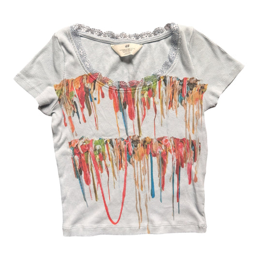 A light gray short-sleeve crop top with a scoop neckline trimmed in silver glitter, featuring a colorful dripping gum graphic across the front.