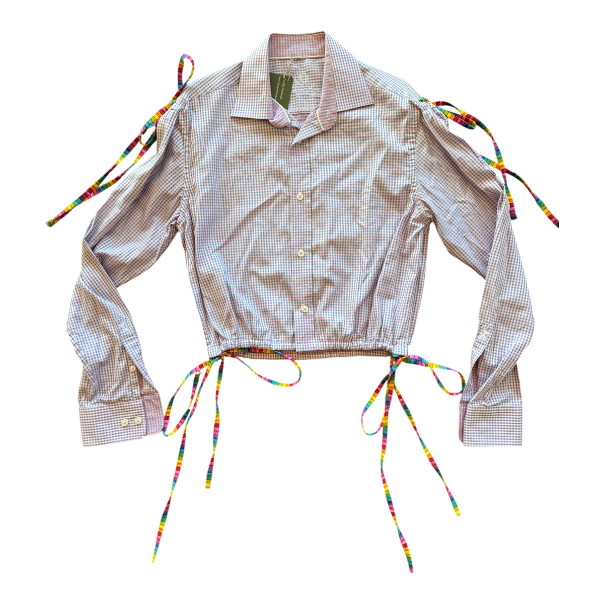 A cropped long-sleeve button-up shirt with a fine checkered pattern in beige and light pink, featuring multicolor rainbow braided tie straps at the shoulders and waist.