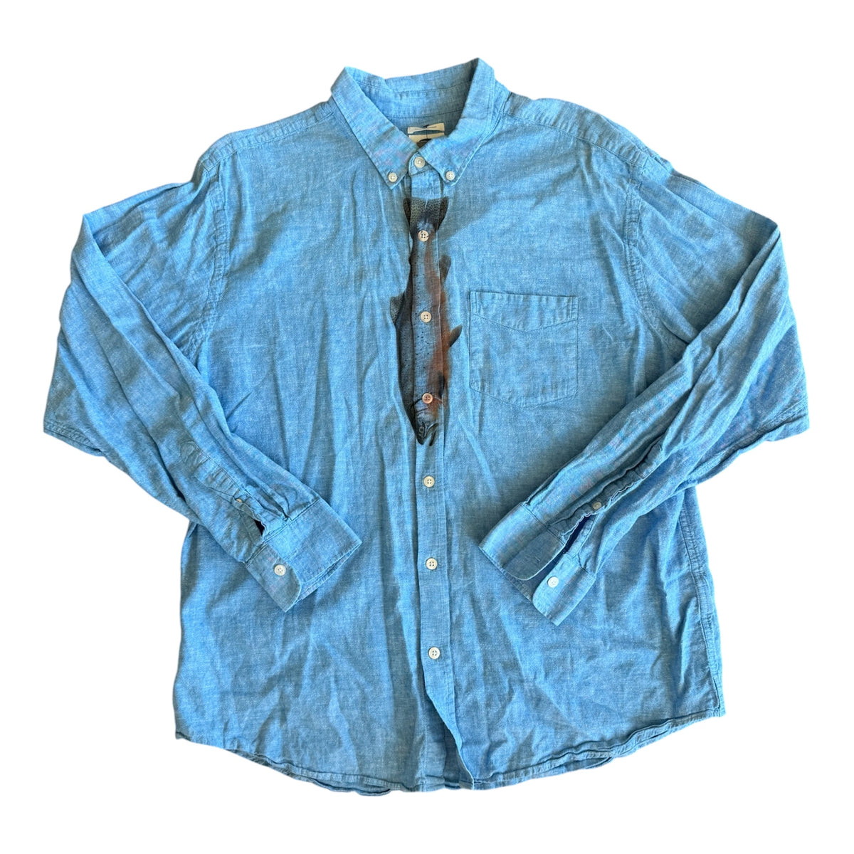 A light blue chambray long-sleeve button-down shirt laid flat on a white background, with a salmon necktie tucked underneath the open collar.