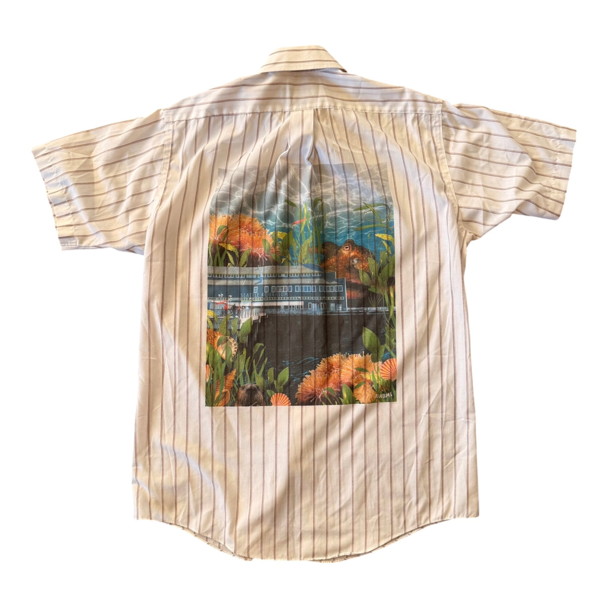 A short-sleeve button-up shirt with thin vertical beige and white pinstripes, featuring a large rectangular graphic print on the back depicting a seattle aquarium scene. 