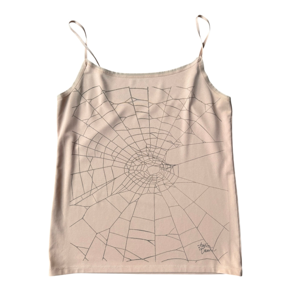 A beige spaghetti-strap camisole tank top featuring a black line-art spiderweb graphic printed across the front, displayed flat against a solid white background.