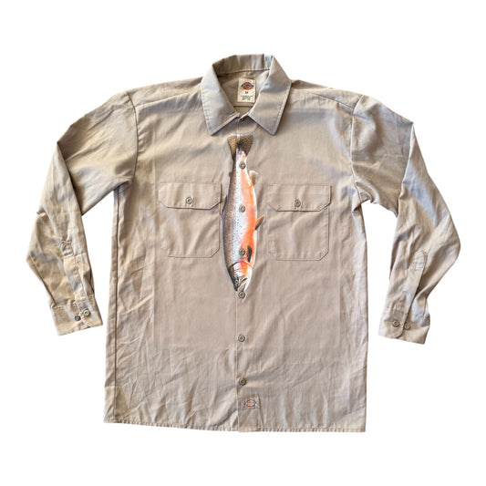 A light beige long-sleeve button-up shirt with a novelty fish-shaped chest pocket and a printed fish graphic on the front, displayed flat against a white background.