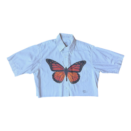 Navy blue and white short sleeve cropped striped button down shirt with a butterfly printed on the chest laid flat against a white background 