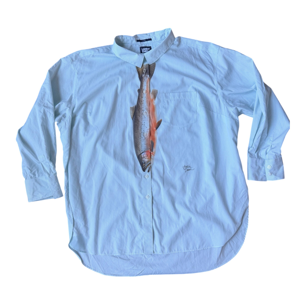Light blue and white striped button down with a trout printed down the front middle to look like a tie. Laid flat against a white background 