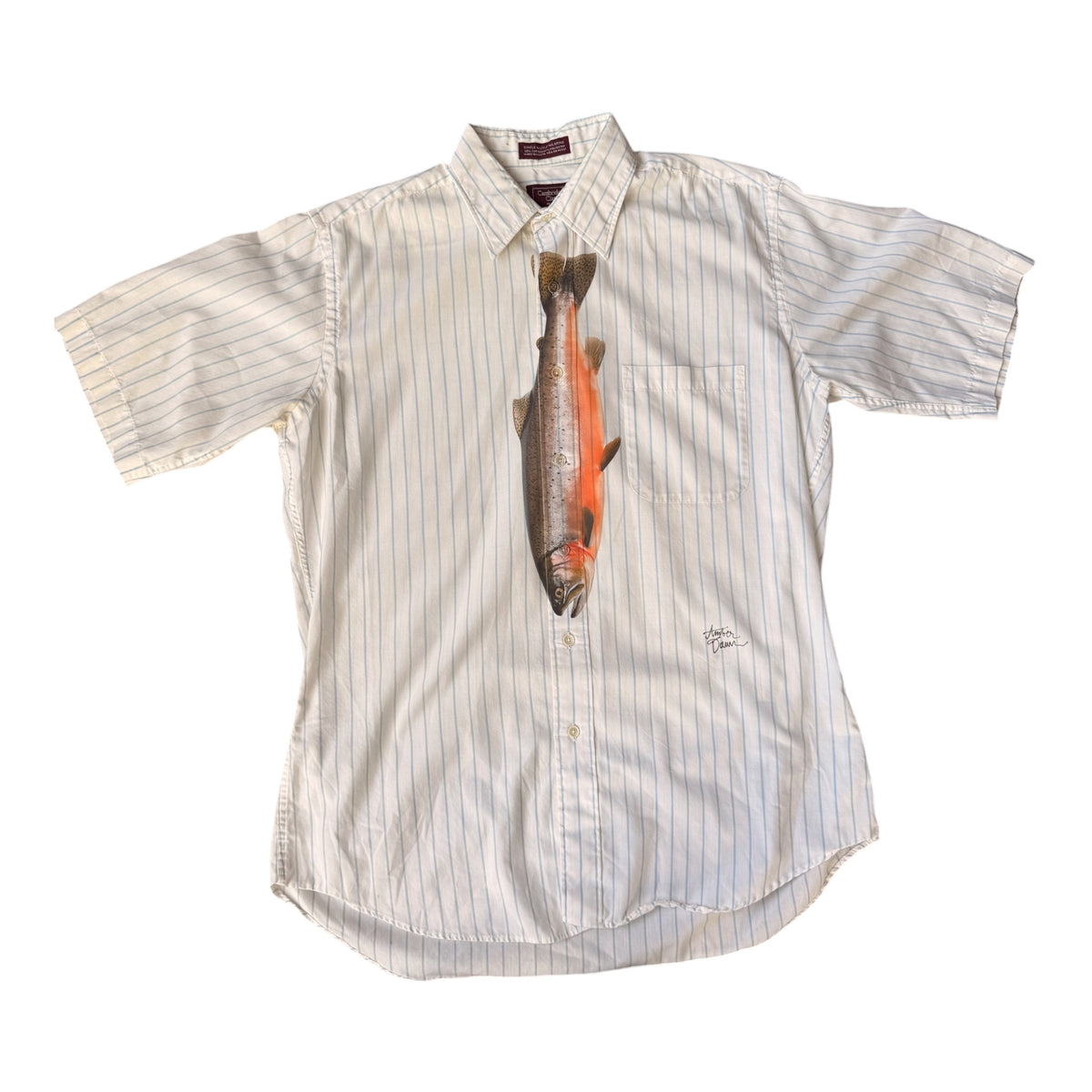 A short-sleeve button-up shirt in off-white with thin vertical pinstripes, featuring a realistic printed fish graphic centered on the chest, laid flat against a white background.