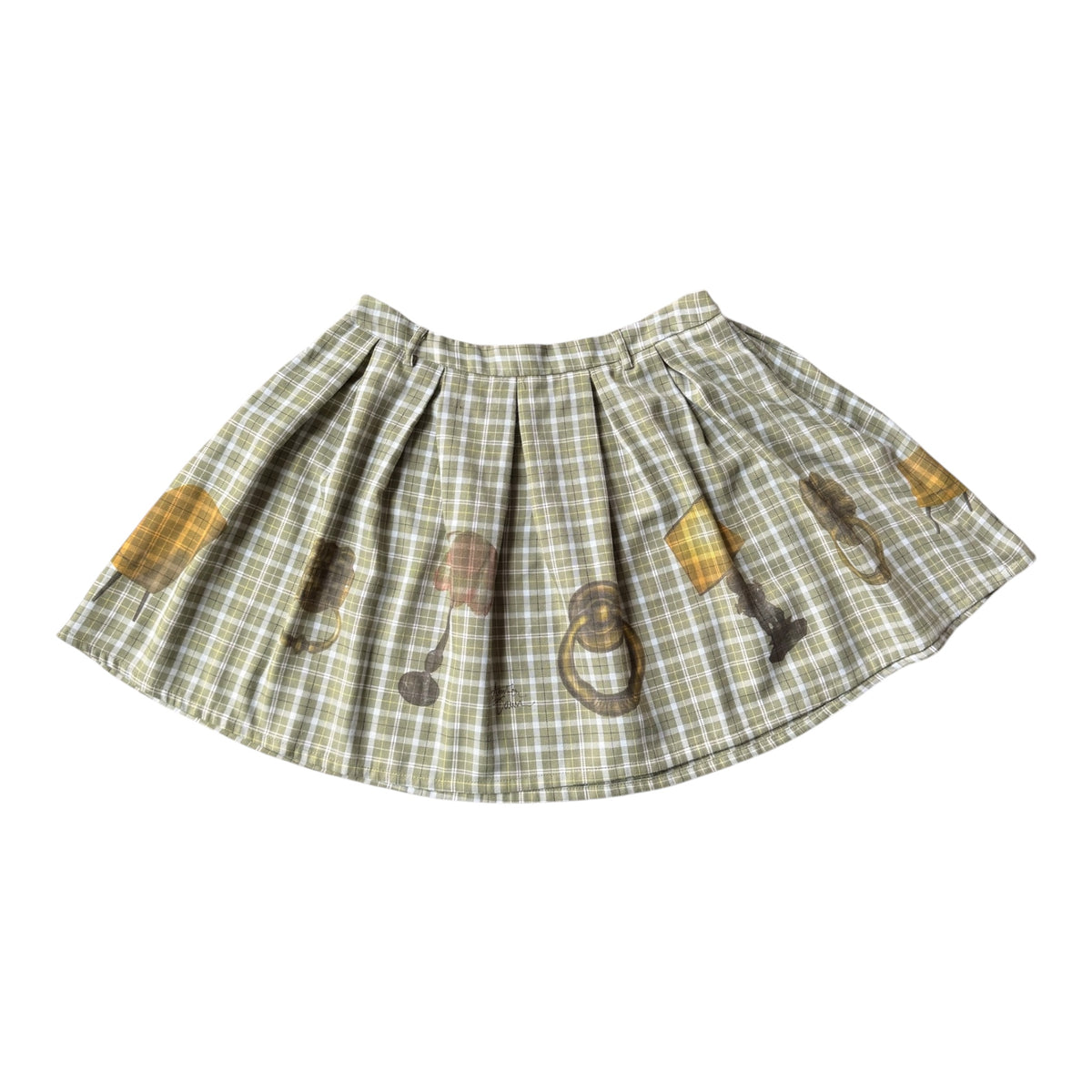 A pleated skirt in a muted green and beige plaid pattern, decorated with illustrations of vintage lamps and door knockers in yellow, brown, and gray, shown against a plain white background.