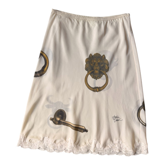 An A-line skirt in cream-colored silk with a print of antique brass door knobs and a lace hem.