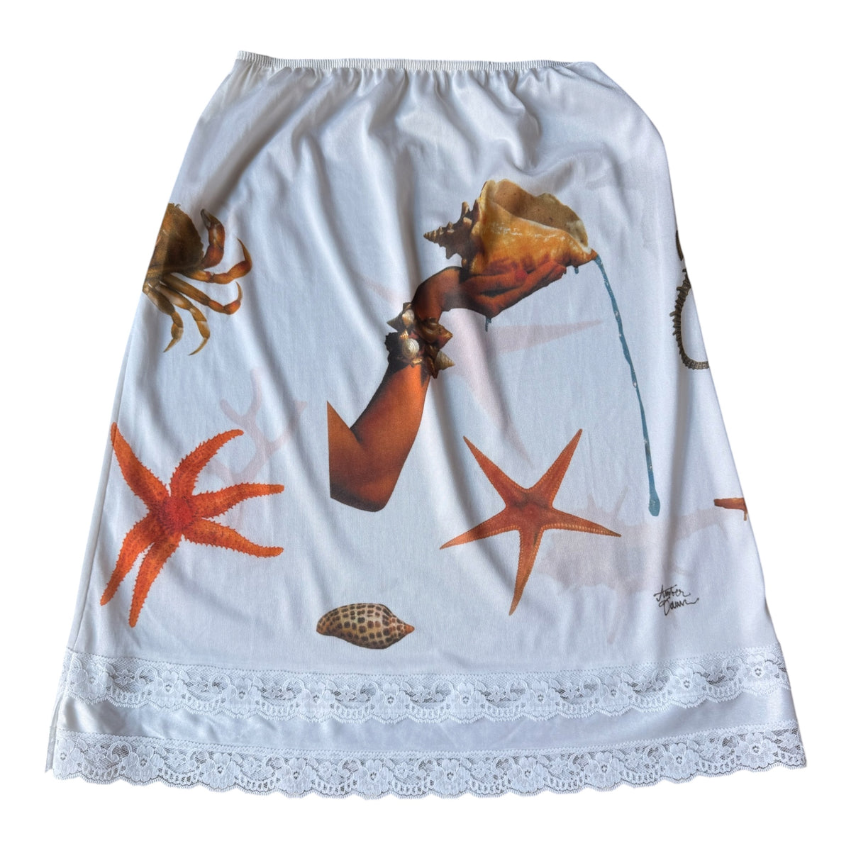 White A-line skirt featuring an ocean-themed print with orange starfish, a brown crab, a seashell and arm, and a white lace hem.