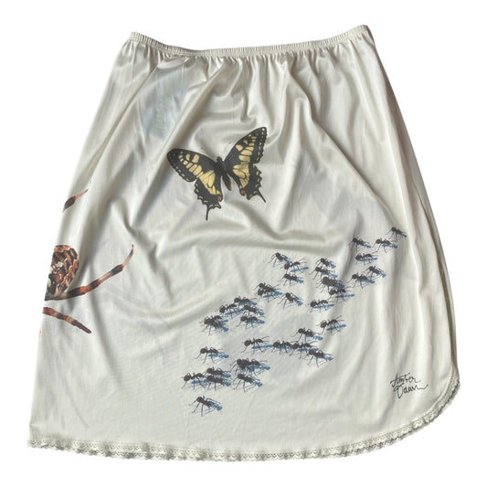 An off-white satin nightgown featuring a butterfly, ants, and spider print, with a lace-trimmed hem.