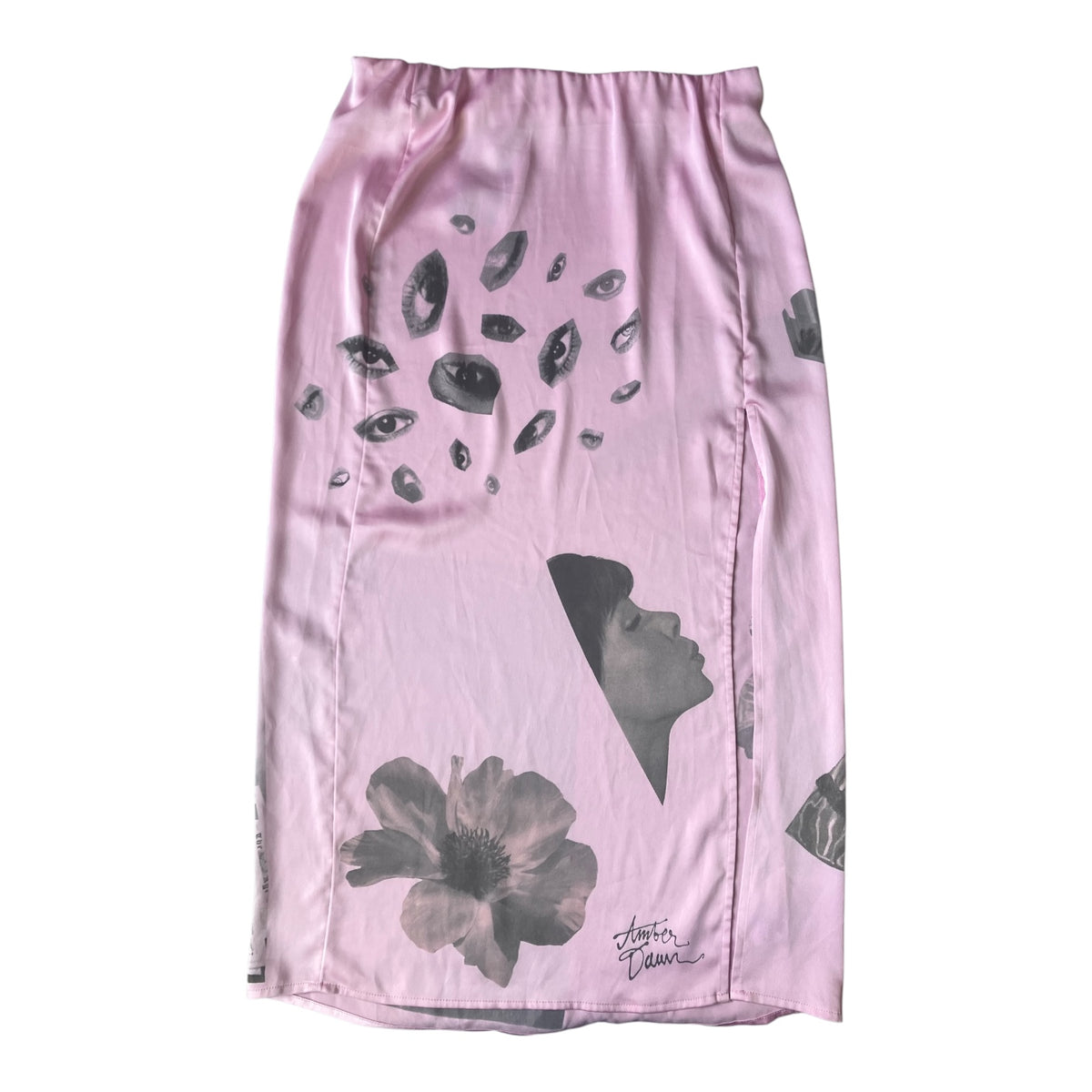 A light pink satin pencil skirt featuring a black and gray artistic print of gemstones, a woman's profile, and a flower