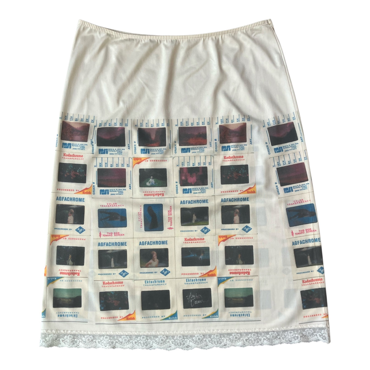 An off-white A-line skirt featuring a grid pattern of vintage film stills with Kodachrome text, finished with a white lace hem.